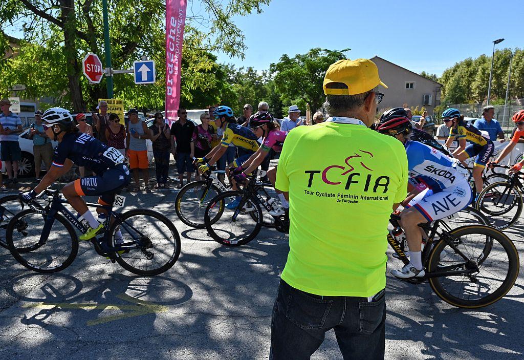Bénévole en tenue TCFIA devant le passage du peloton pendant l’événement